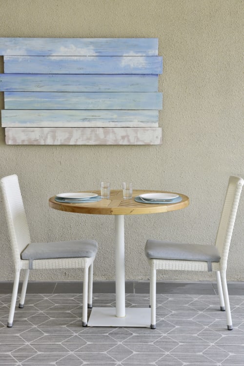 Modern dining area at Pointe d'Esny beachfront apartment with round wood table, white chairs, and coastal blue wall art