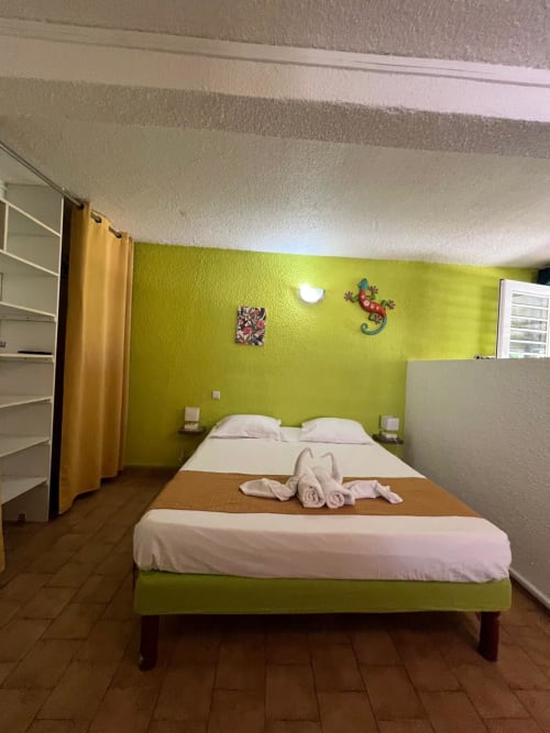 Chambre vert citron lumineux aux 2 Cocotiers à Sainte-Luce avec lit queen-size, oreillers blancs et décoration colorée