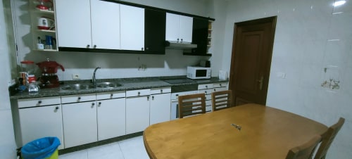Cucina e zona pranzo moderni nell'Apartamento San Antonio, Monforte de Lemos con armadietti bianchi, ripiani in granito e
