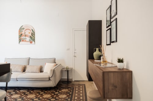 Modern bedroom at Casanova B&B in Cefalù with beige sofa, wooden dresser, and minimalist décor