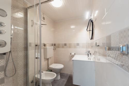Bagno moderno della camera Francesco al Casanova B&B, Cefalù con doccia walk-in, toilet, bidet e lavabo bianco