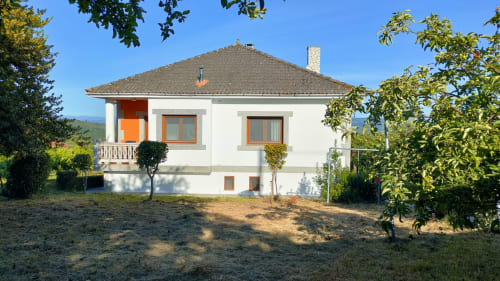White villa Casa Pedro in Pantón with orange trim, terrace, and surrounding gardens in Galicia