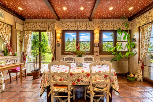 Elegante comedor de Basque Palace B&B en Laukariz con muebles florales, techo ornamentado y vistas al jardín