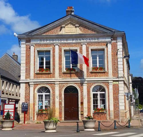 Bâtiment historique en brique avec drapeau français, gîte Clos Céleste à Écrainville, région d'Étretat