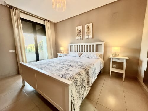 Dormitorio moderno en apartamento Pataconablue playa de Valencia con cama blanca, decoración neutral, acceso a balcón y vistas al mar