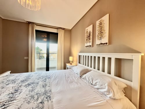 Dormitorio moderno y luminoso con cama blanca, balcón y paredes beige cálido en Pataconablue Rentals, Valencia