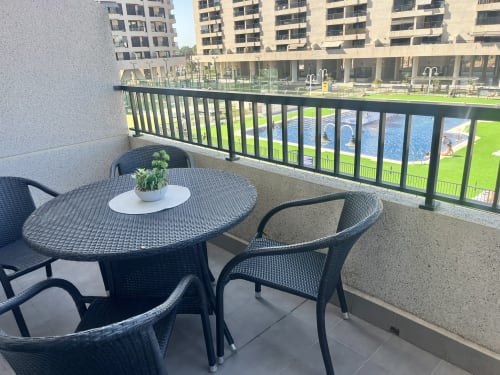 Balcón privado con muebles de mimbre con vistas a la piscina y playa del apartamento Pataconablue Valencia