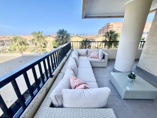 Amplia terraza de Pataconablue Rentals en Valencia con muebles grises, vistas al mar Mediterráneo y palmeras