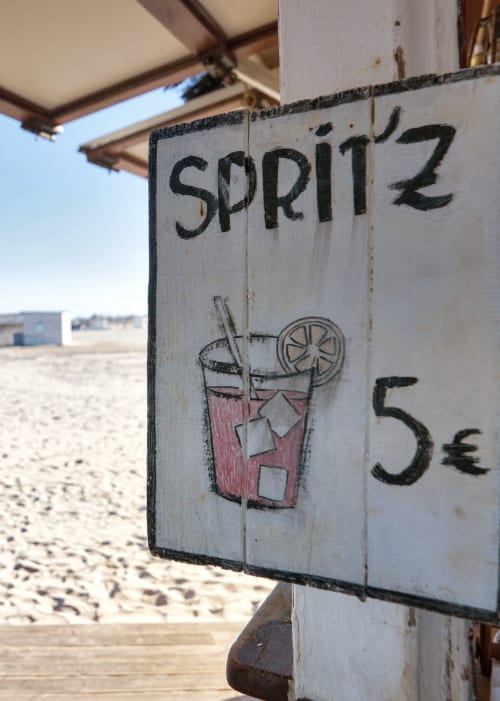 Letrero de spritz junto a la playa con ilustración de bebida y precio de 5€ en el complejo de apartamentos Pataconablue Valencia