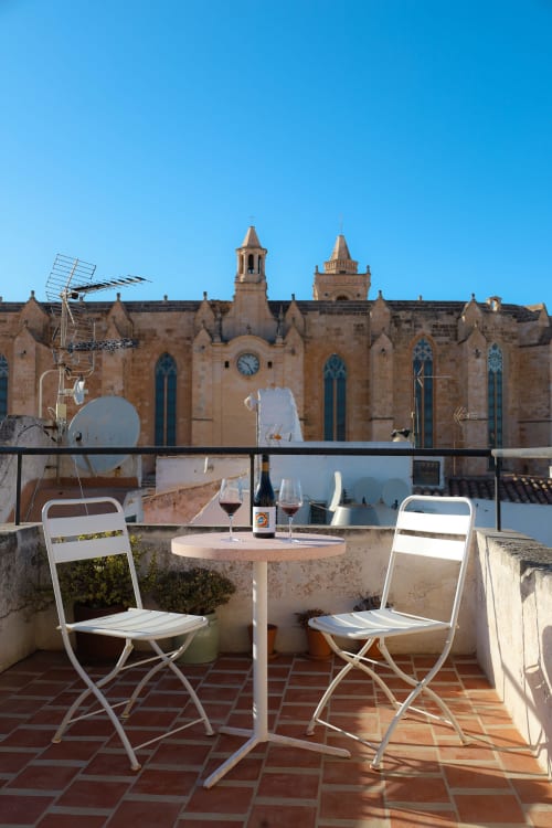 Rooftop dining at Hotel Fragile in Ciutadella with wine overlooking a historic stone church, Menorca
