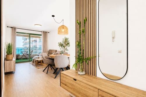 Sala de estar moderna con vistas al mar, muebles de madera, asientos contemporáneos e iluminación colgante