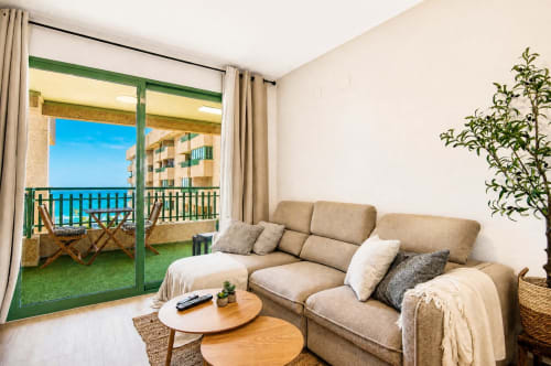 Salón de apartamento frente al mar en Valencia con vistas al mar, sofá cómodo y acceso al balcón
