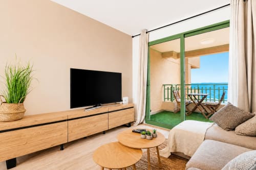 Apartamento moderno en Valencia con vistas al mar, televisor de pantalla plana, muebles de madera y terraza abierta con vista al Mediterráneo