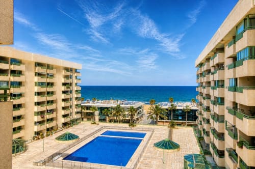 Complejo de apartamentos frente al mar en Valencia con piscina, vista al mar y palmeras con vista a la playa mediterránea