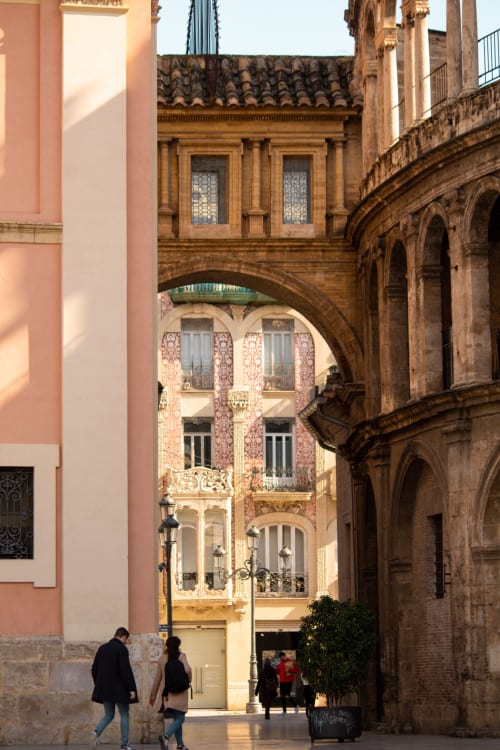 Callejón histórico de Valencia con edificios ornamentados y arco, ubicación de alquiler Pataconablue
