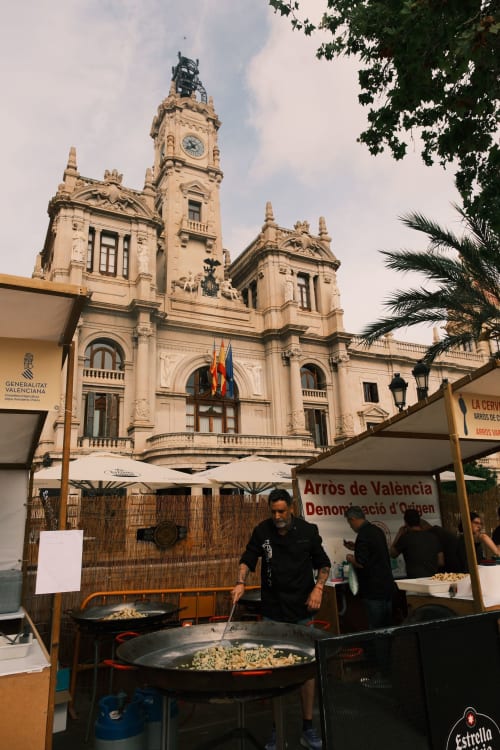 Puesto de paella valenciana frente a la torre del reloj histórica en el centro de la ciudad de Valencia, España