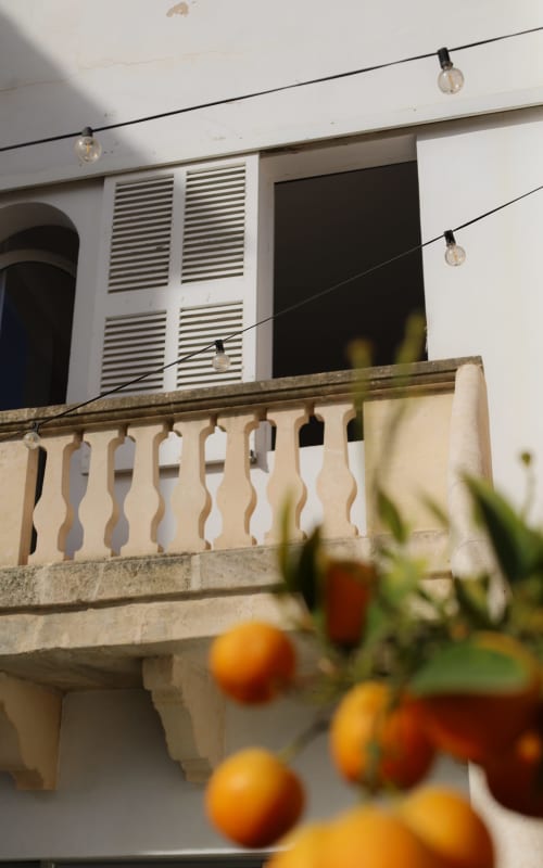 Hotel Fragile balcony in Ciutadella de Menorca with stone railing, string lights, and fresh citrus fruits in foreground