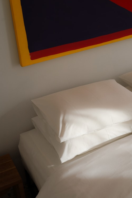 White pillows on bed at Hotel Fragile in Ciutadella de Menorca, modern decor with colorful artwork above