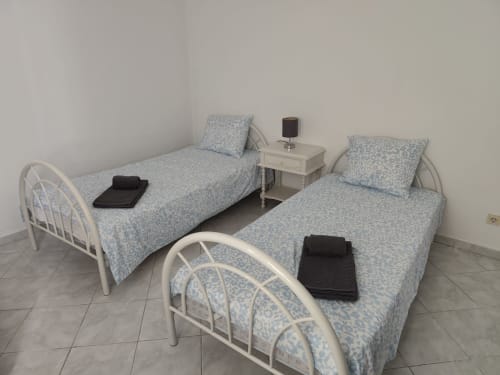 Quarto duplo no apartamento CASA FLOR da Albufeira Inn, com duas camas de estrutura metálica branca e roupa de cama azul estampada