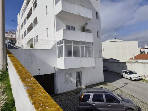 Edifício residencial moderno branco no centro de Albufeira com carro estacionado e varandas com vista para o mar