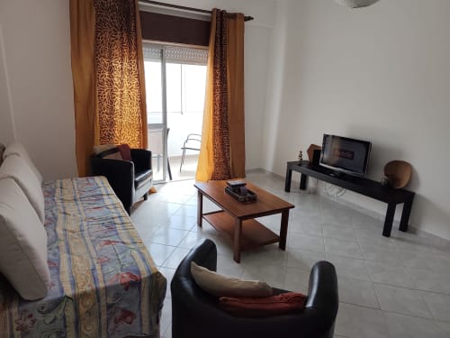 Sala de estar espaçosa no apartamento CASA FLOR da Albufeira Inn com cama, móveis, TV e acesso à varanda