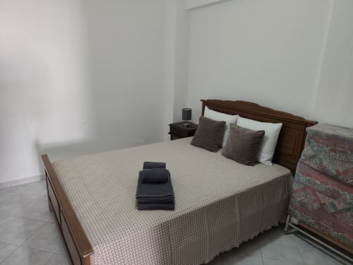 Quarto do apartamento CASA FLOR em Albufeira Inn com cama de madeira, almofadas marrons e vista da cidade em Albufeira, Portugal