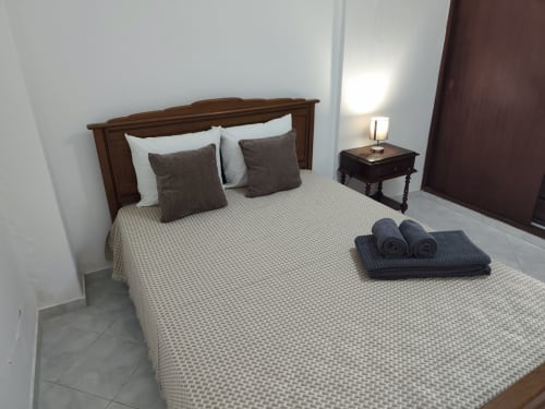 Quarto do apartamento CASA FLOR na Albufeira Inn, com cama de madeira, almofadas e toalhas enrolladas