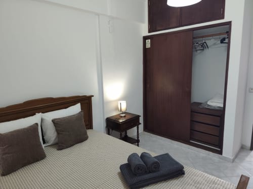 Quarto espaçoso na Albufeira Inn com cama de madeira, guarda-roupa e comodidades de apartamento no centro da cidade
