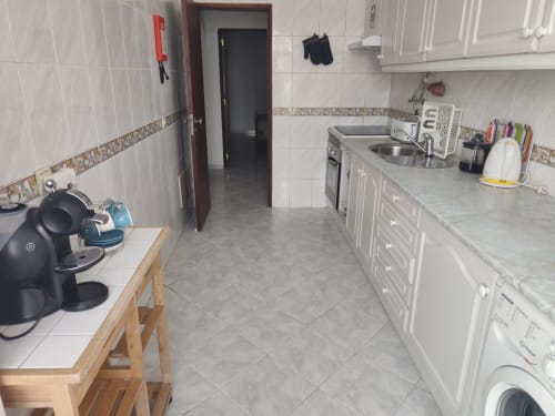 Cozinha moderna no apartamento CASA FLOR da Albufeira Inn, com armários brancos, eletrodomésticos em aço inoxidável e área de refeições