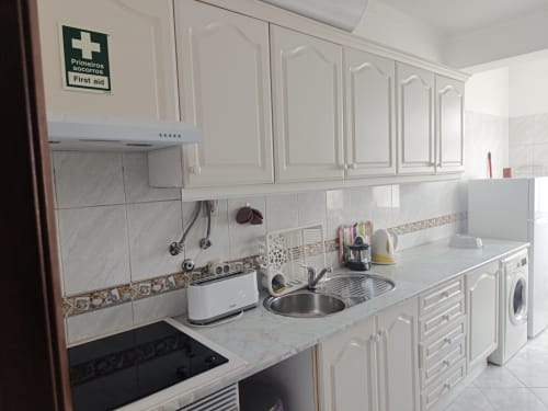 Cozinha moderna branca no apartamento CASA FLOR do Albufeira Inn com pia em aço inoxidável, fogão, máquina de lavar e prim