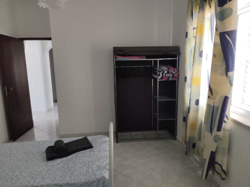 Quarto amplo do apartamento CASA FLOR na Albufeira Inn com cama, guarda-roupa preto e janela com vista para a cidade