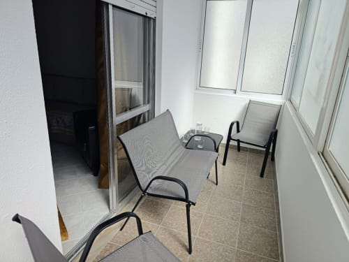 Zona de estar na varanda do Albufeira Inn com vista para a cidade, com cadeiras e mesa cinzentas no apartamento CASA FLOR, Albufeira