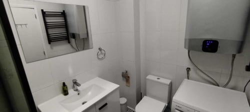 Casa de banho moderna do apartamento Albufeira Inn com lavatório, sanita, toalheiro aquecido e espelho