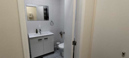 Banheiro moderno com penteadeira branca, espelho, vaso sanitário e piso em azulejos pretos no apartamento Albufeira Inn, Portugal