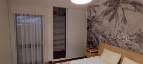 Quarto moderno no Albufeira Inn com cama de madeira, mural na parede, guarda-roupa embutido e porta de vidro com acesso ao terraço
