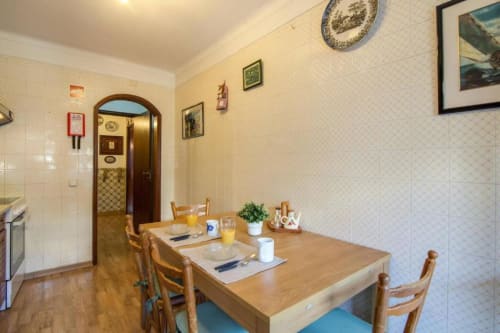 Zona de refeições em apartamento T2 do Albufeira Inn com mesa de madeira, cadeiras e vista para a cozinha