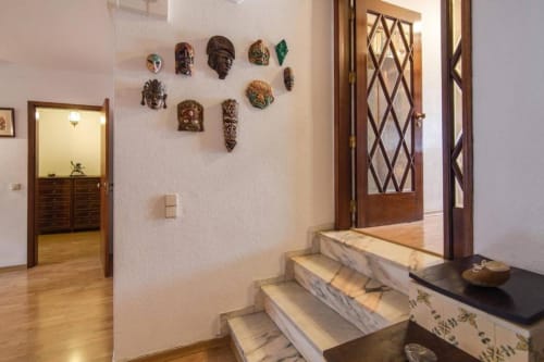 Corredor do apartamento Albufeira Inn com escadas de mármore, máscaras decorativas na parede, portas de madeira e vista da cidade em Portugal
