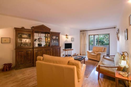 Espaçosa sala de estar do apartamento Albufeira Inn com sofá de couro amarelo, armário de madeira e varanda com vista para