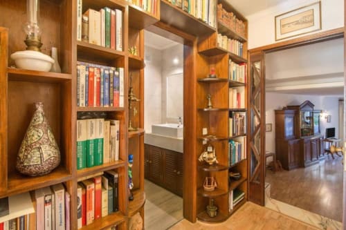 Corredor com estante de madeira no apartamento Albufeira Inn com livros, objetos decorativos e vista para banheiro e sala