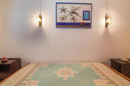 Quarto do Albufeira Inn com tapete turquesa, arandelas de parede e arte temática costeira acima da cama