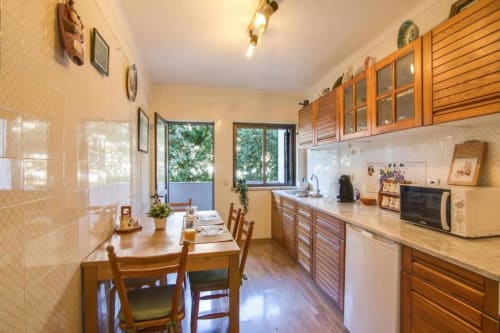 Cozinha-sala iluminada no apartamento Albufeira Inn com móveis em madeira, mesa de jantar e varanda com vista para a cidade