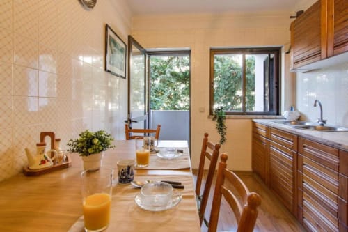 Cozinha e sala de jantar do apartamento Albufeira Inn com mesa de madeira, cadeiras, pia e vista para a varanda