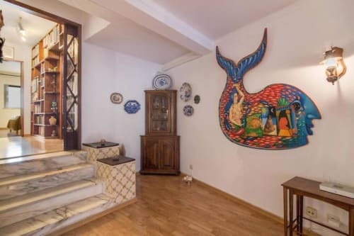 Interior do apartamento Albufeira Inn com arte de baleia na parede, móveis de madeira, pratos de cerâmica azul e escadas de mármore