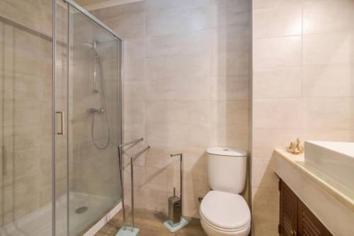 Banheiro moderno com chuveiro aberto, sanita e lavatório no apartamento Albufeira Inn, Albufeira Portugal