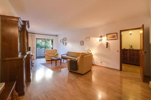 Sala de estar espaçosa no apartamento Albufeira Inn com pisos de madeira, móveis em couro bege e decoração moderna com vista