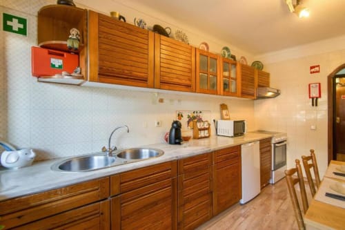 Cozinha espaçosa no apartamento Albufeira Inn com armários em madeira, pia em aço inox e área de refeições com cadeiras