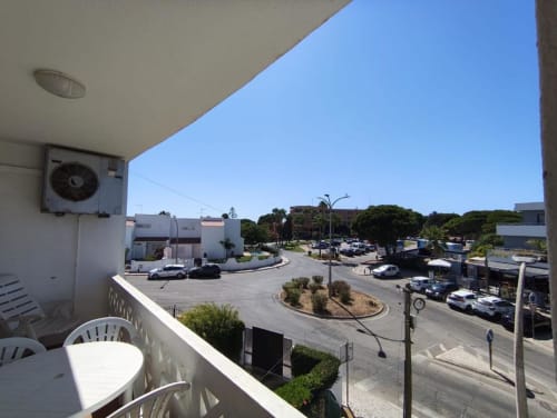 Vista da varanda do Albufeira Inn com vista para estacionamento, edifícios residenciais e árvores da rua em dia ensolarado e claro