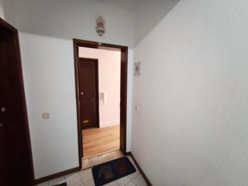 Entrada de corredor luminosa com paredes brancas, portas de madeira escura e piso em azulejo do apartamento Albufeira Inn perto da Praia dos