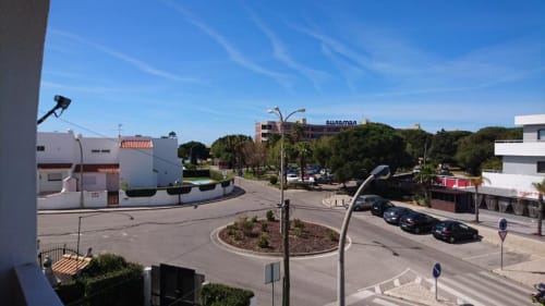 Varanda da Albufeira Inn com vista para a rua, carros estacionados e árvores em Praia dos Aveiros, Portugal