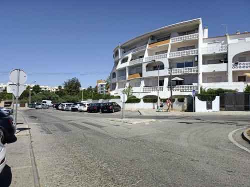 Edifício do Albufeira Inn em Portugal com fachada branca curva, varandas e área de estacionamento num dia ensolarado